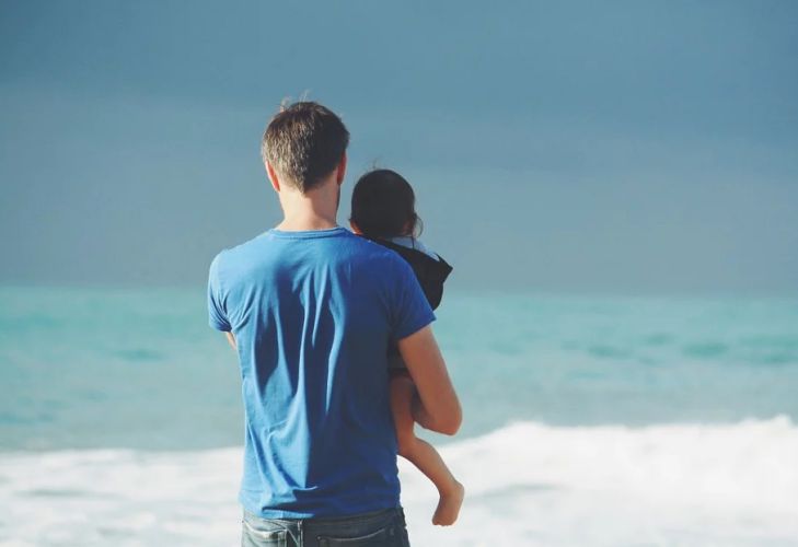 отец держит на руках ребёнка, берег