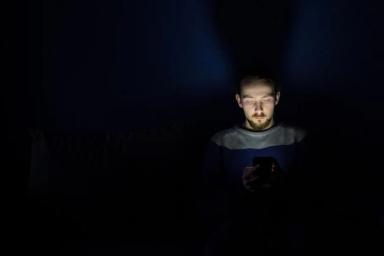 мужчина со смартфоном в темноте
