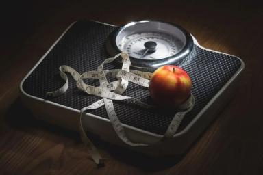 мерная лента и яблоко на весах